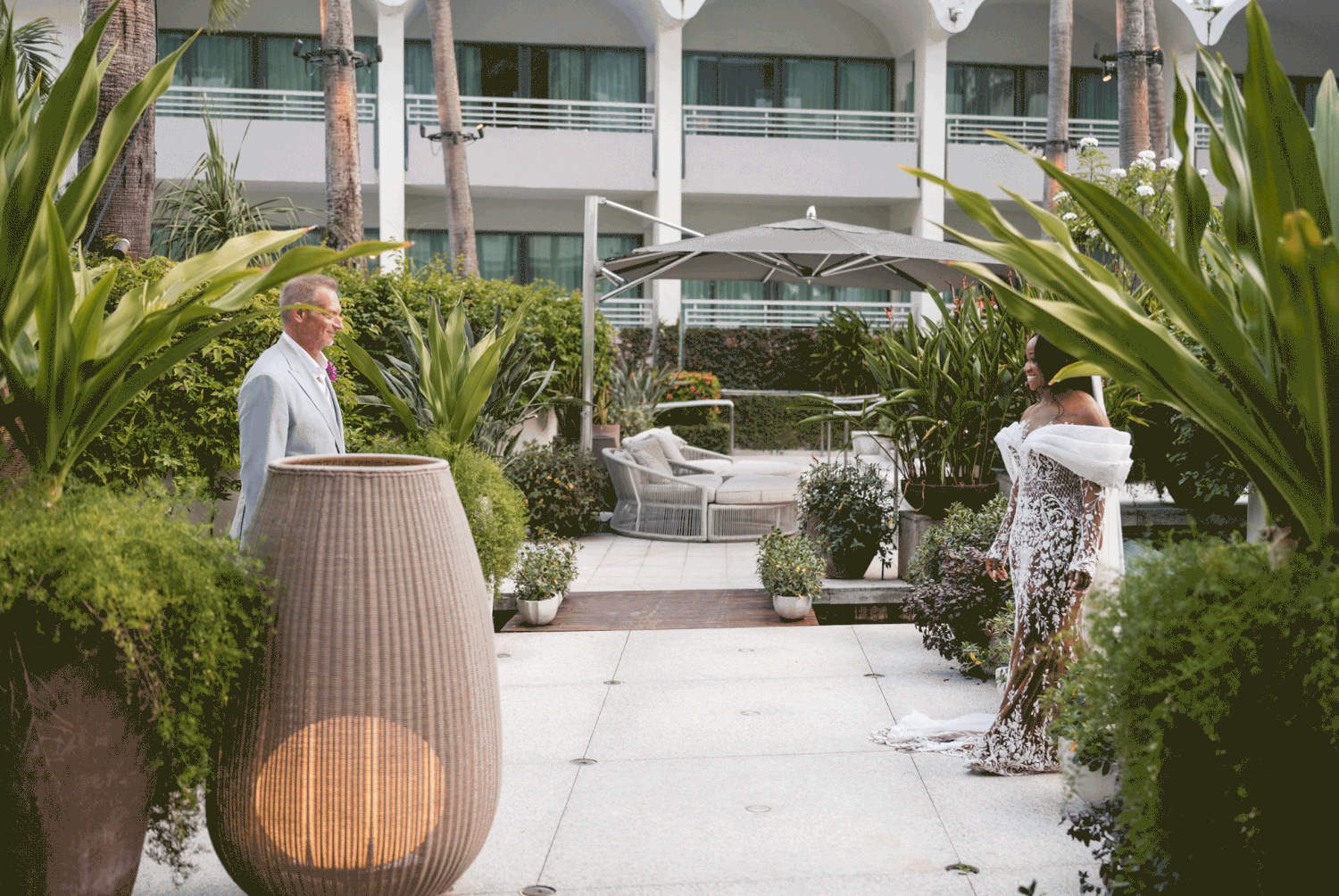 Bride and groom walking down a tropical garden aisle surrounded by lush greenery during an outdoor wedding ceremony at La Concha Hotel