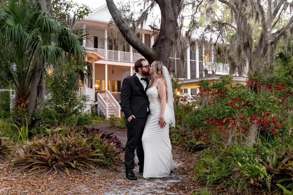 Bride and groom share a romantic moment on a garden path outside a Southern plantation wedding venue.