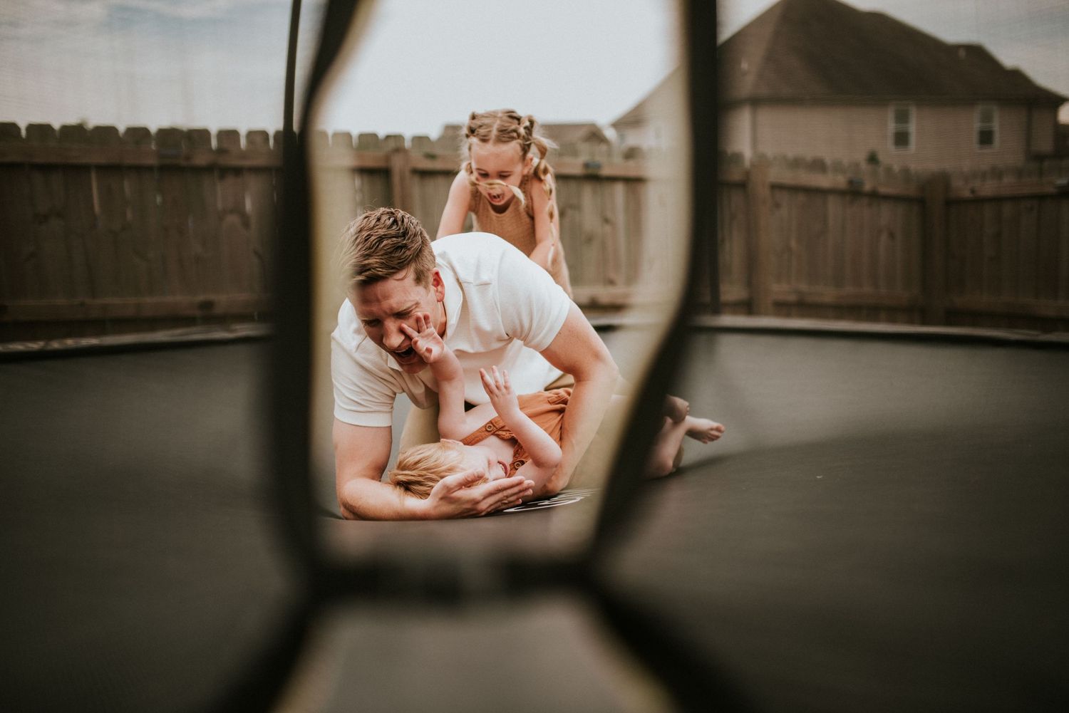 father and kids playing on the trampoline during a lifestyle in home session with Karina cantu Photography.