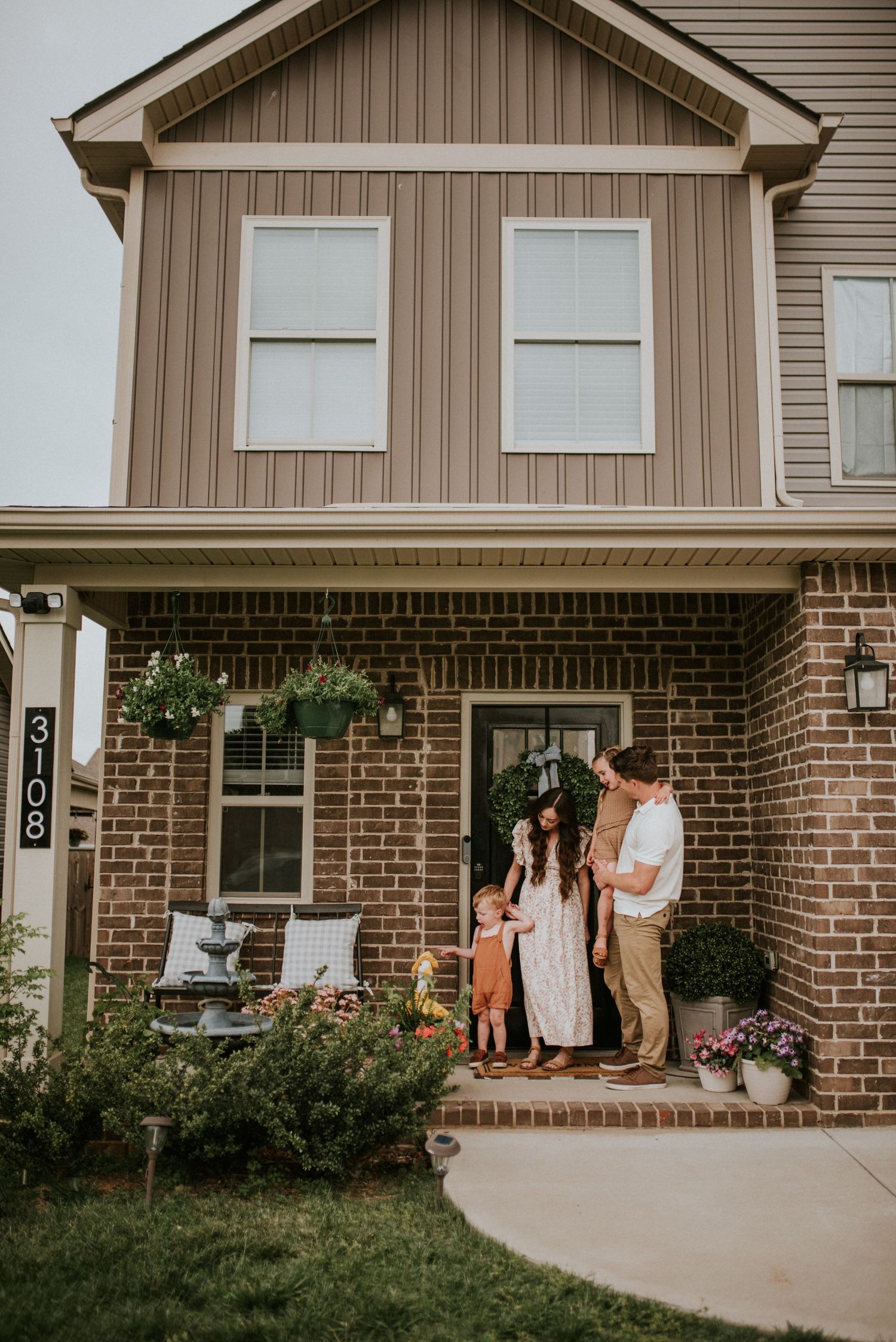 Family of four standing outside their house during a lifestyle in home session with Karina Cantu Photography.
