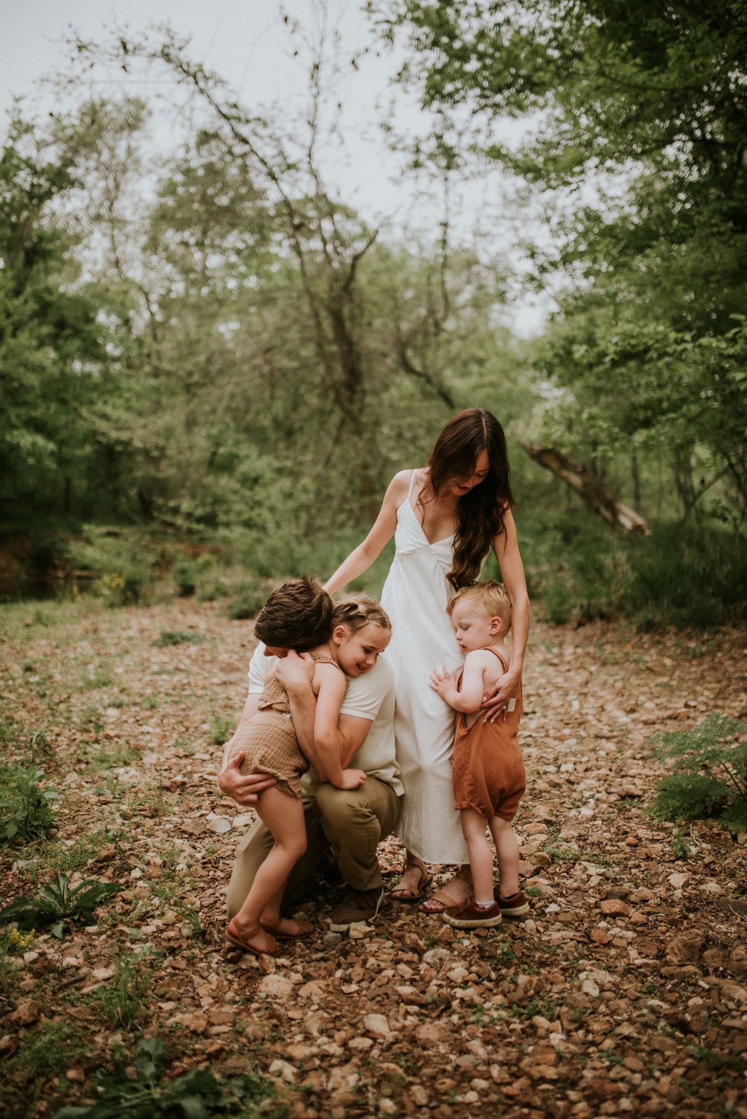 Family photo with dad hugging daughter and mom's hand is gently hugging their son at the creek in Clarksville, Tennessee.