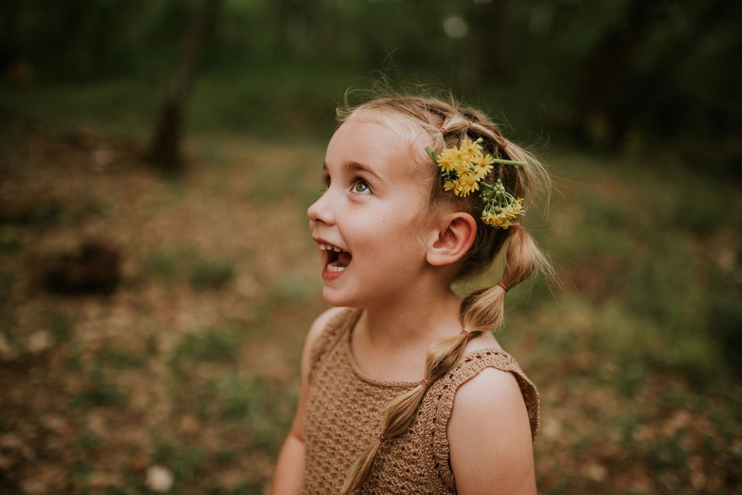Girl with a big smile and flowers in her hair at the creek during a family photography session by the creek in Clarksville, Tennessee.