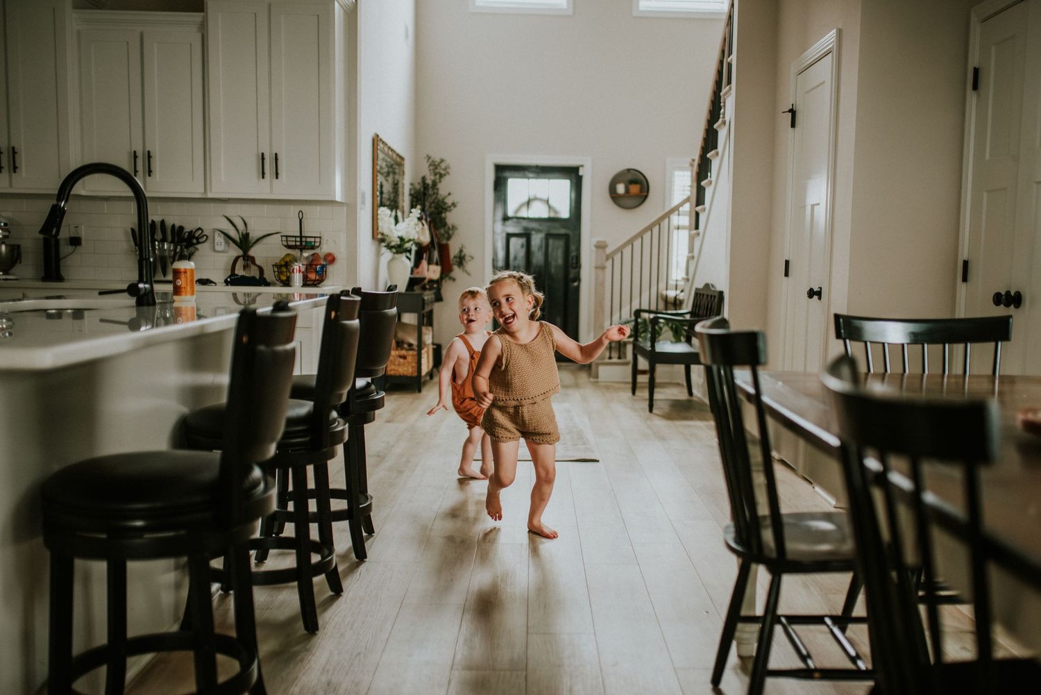 Kids running through the house during an indoor lifestyle session as they play with their parents.