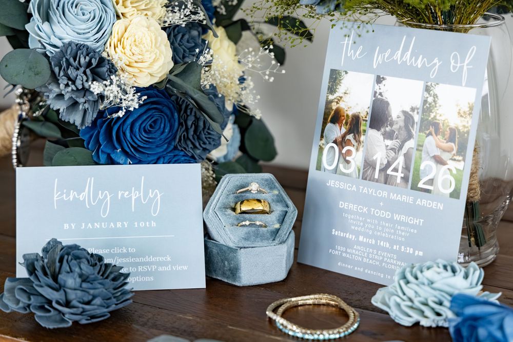 Blue and white wedding stationery suite with ring box, floral arrangements, and reply card on elegant display.