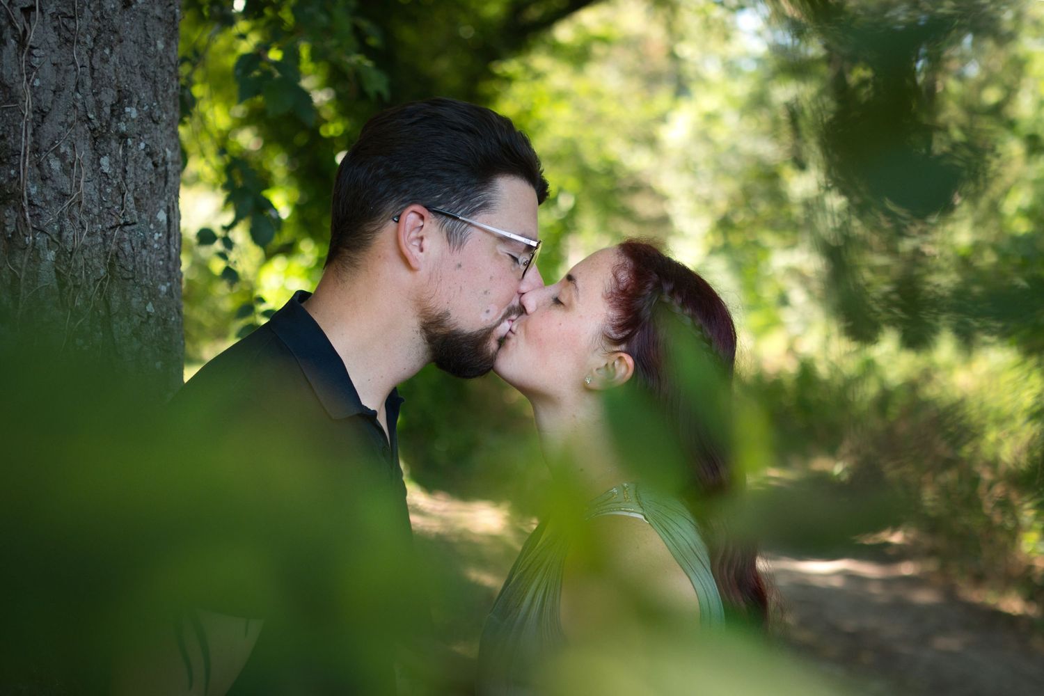 Photo d'un couple en train de s'embrasser dans la forêt.