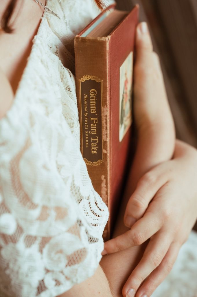 Woman in lace dress holding a vintage copy of Grimm's Fairy Tales illustrated by Fritz Kredel.