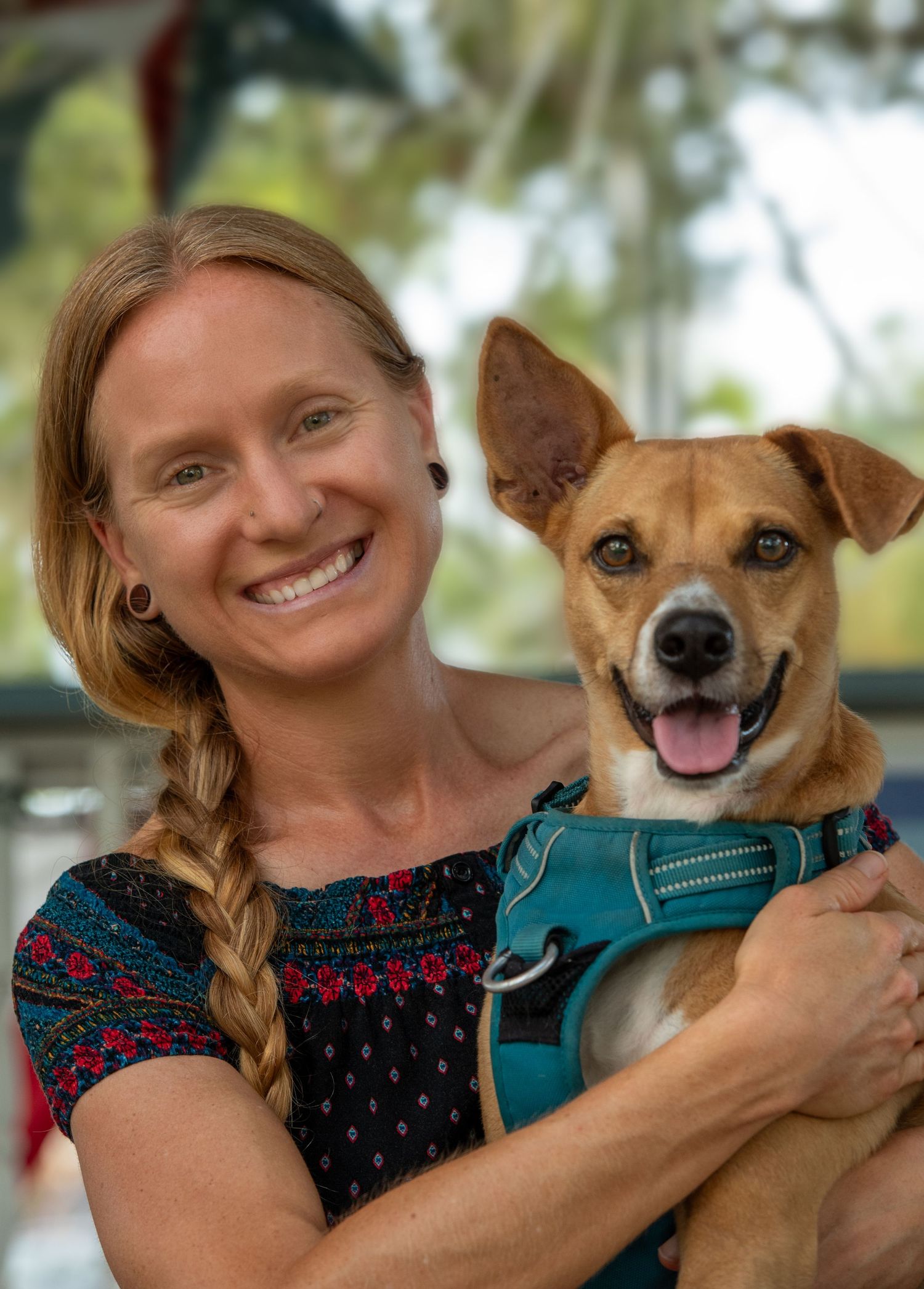 Woman and her dog sharing a happy moment, sitting together on a rock in the park.