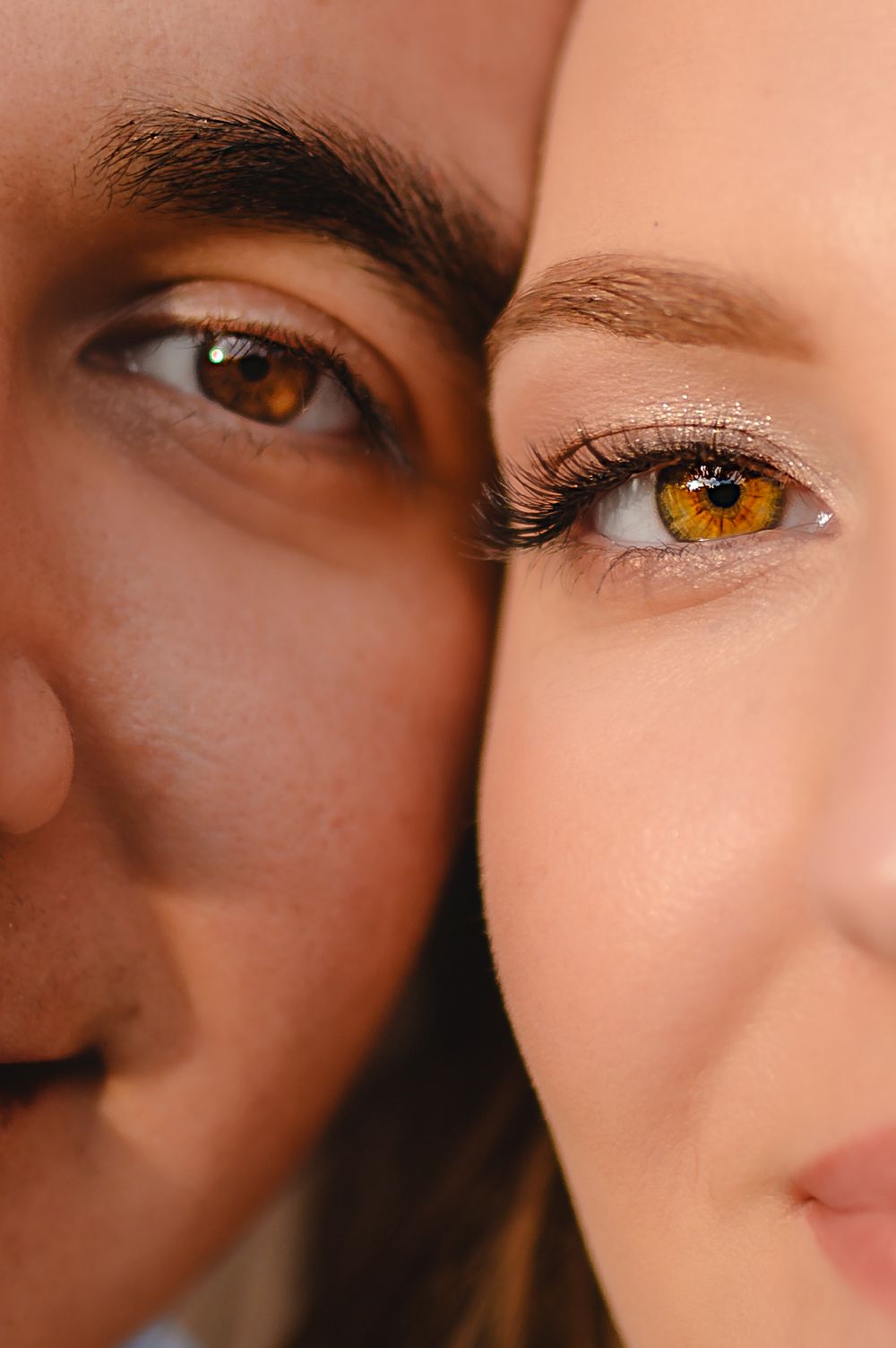Close-up of two people with striking amber-brown eyes side by side, one with natural skin and one with light makeup.