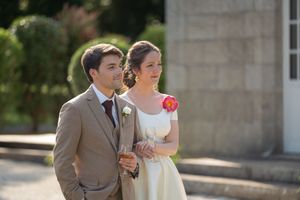 Les mariés se promènent ensemble en plein air ; la mariée porte une robe blanche agrémentée d'une ceinture à motifs floraux colorés.