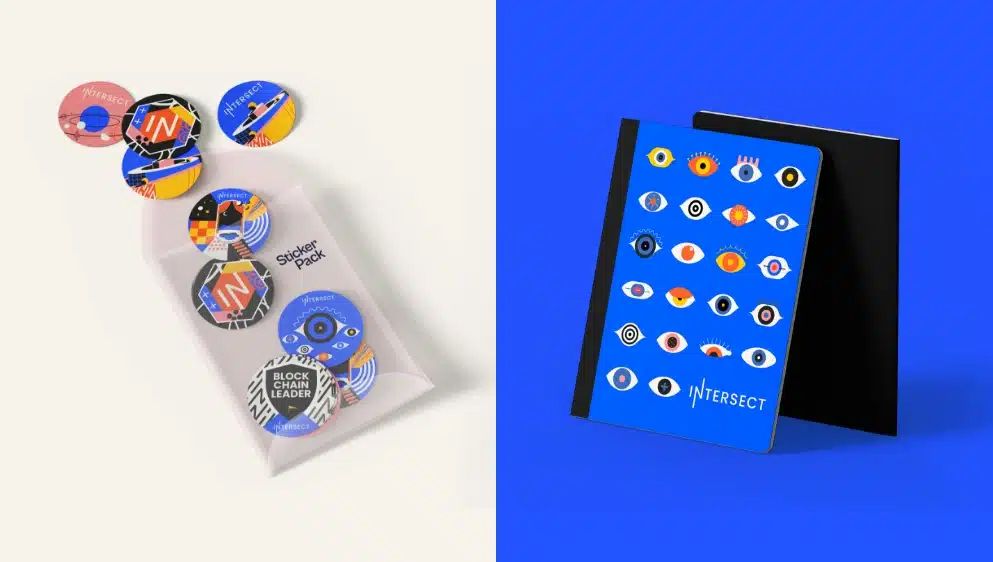 Colorful pin button badges in packaging alongside a blue notebook with eye pattern design.