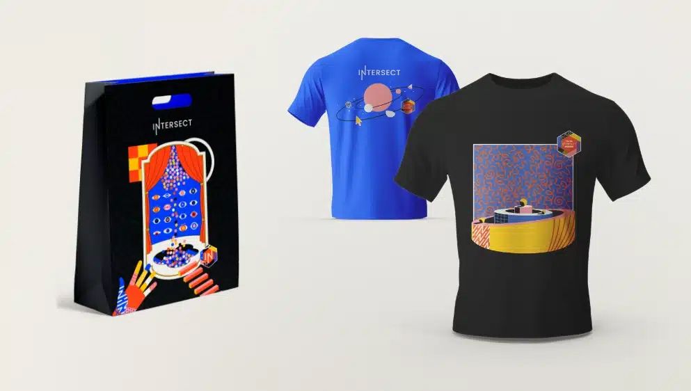 Blue graphic t-shirt and black t-shirt with planet design displayed next to a colorful gift bag.