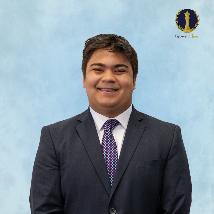 Young man in navy suit and purple tie smiling professionally against a light blue background with a chess logo.
