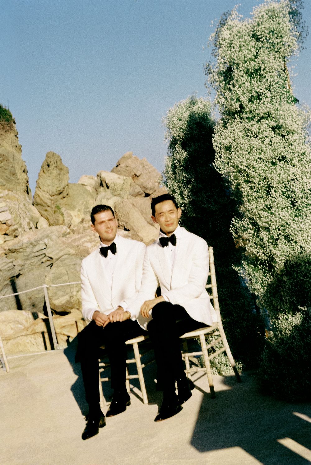 Same sex couple destination wedding LGBTQ+ photographer  at outdoor wedding ceremony with rocky backdrop.