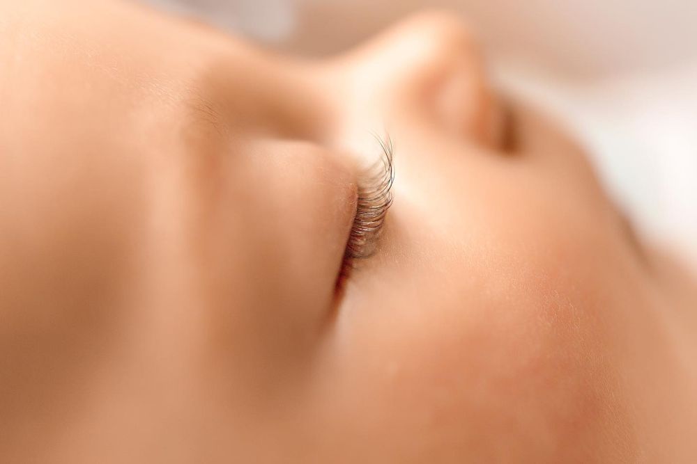 Close-up of a baby's closed eye with long, curled eyelashes against smooth, fair skin.