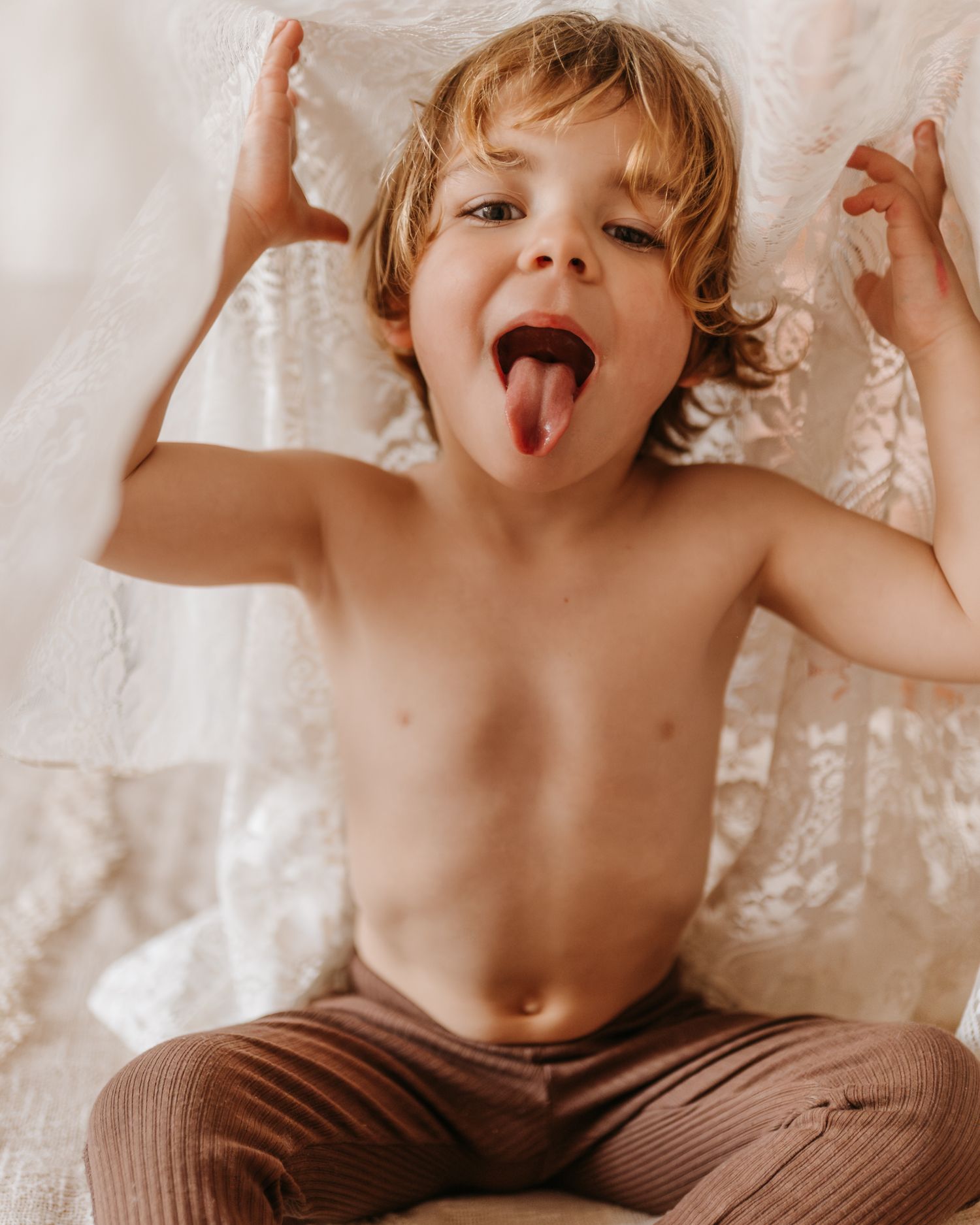 Niño sonriendo durante una sesión de fotografía infantil natural en estudio.