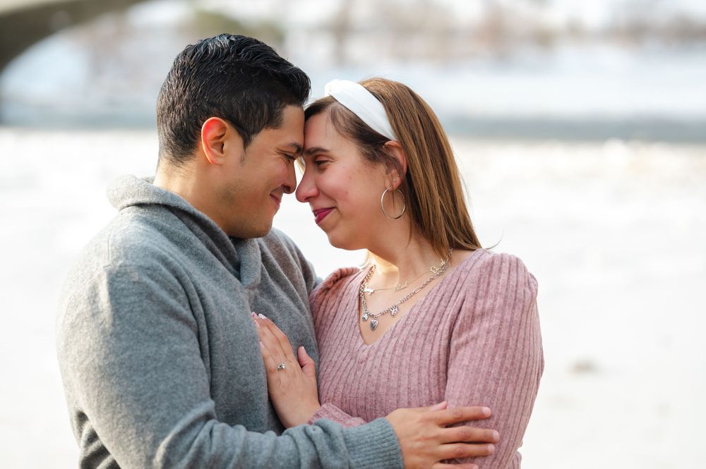 A romantic couple sharing an intimate moment outdoors in winter, smiling and embracing tenderly.