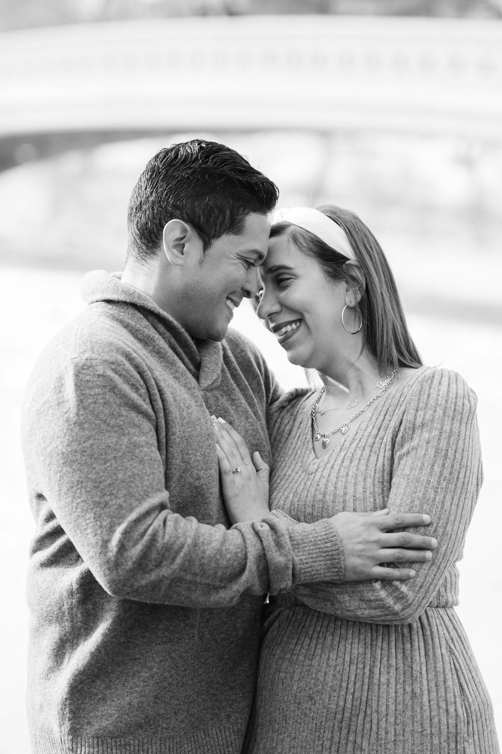 Black and white portrait of joyful engaged couple embracing and smiling at each other in Central Park.