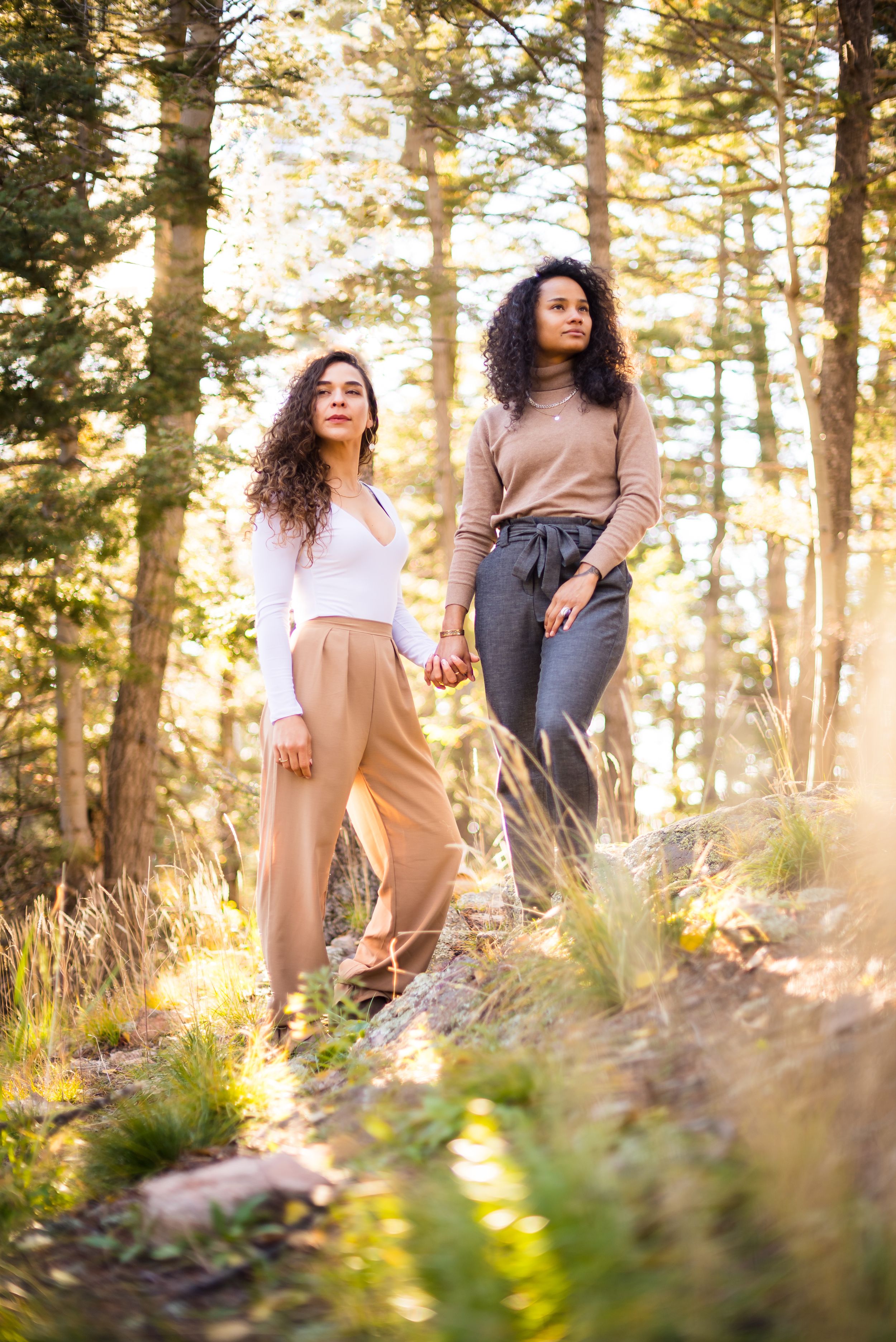 Two friends enjoying a sunlit moment together on a forest trail during golden hour.
