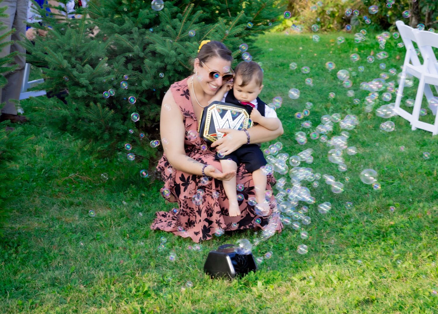 Wedding couple with elderly guest celebrating outdoors with a fountain sparkler on a sunny day.