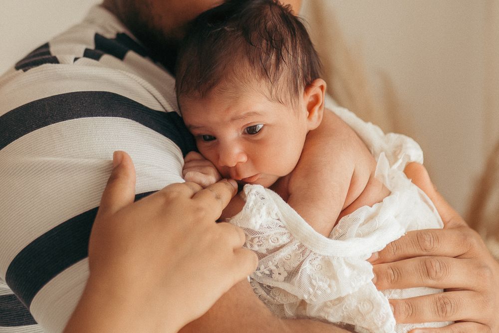 Padre abrazando a su bebé durante una sesión de fotografía natural y espontánea de recién nacido en el estudio de La Cellera de Ter, Girona