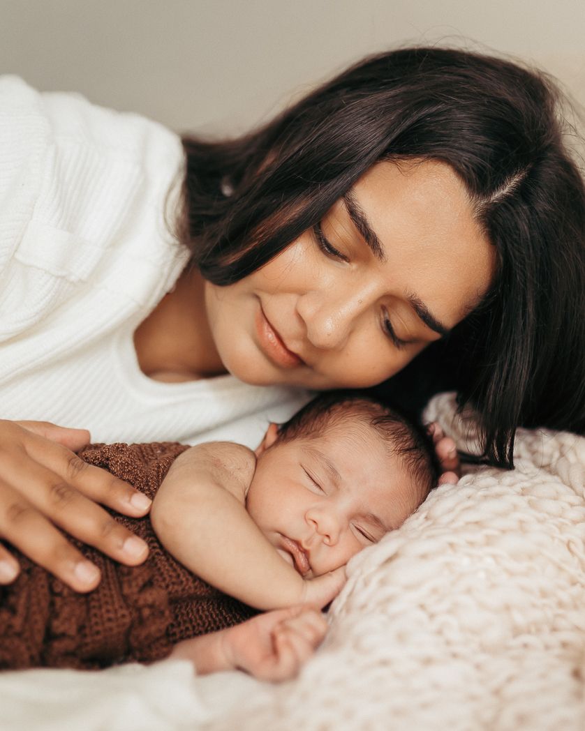 Madre abrazando a su bebé recién nacido en una sesión de fotografía newborn con luz natural en La Cellera de Ter, Girona