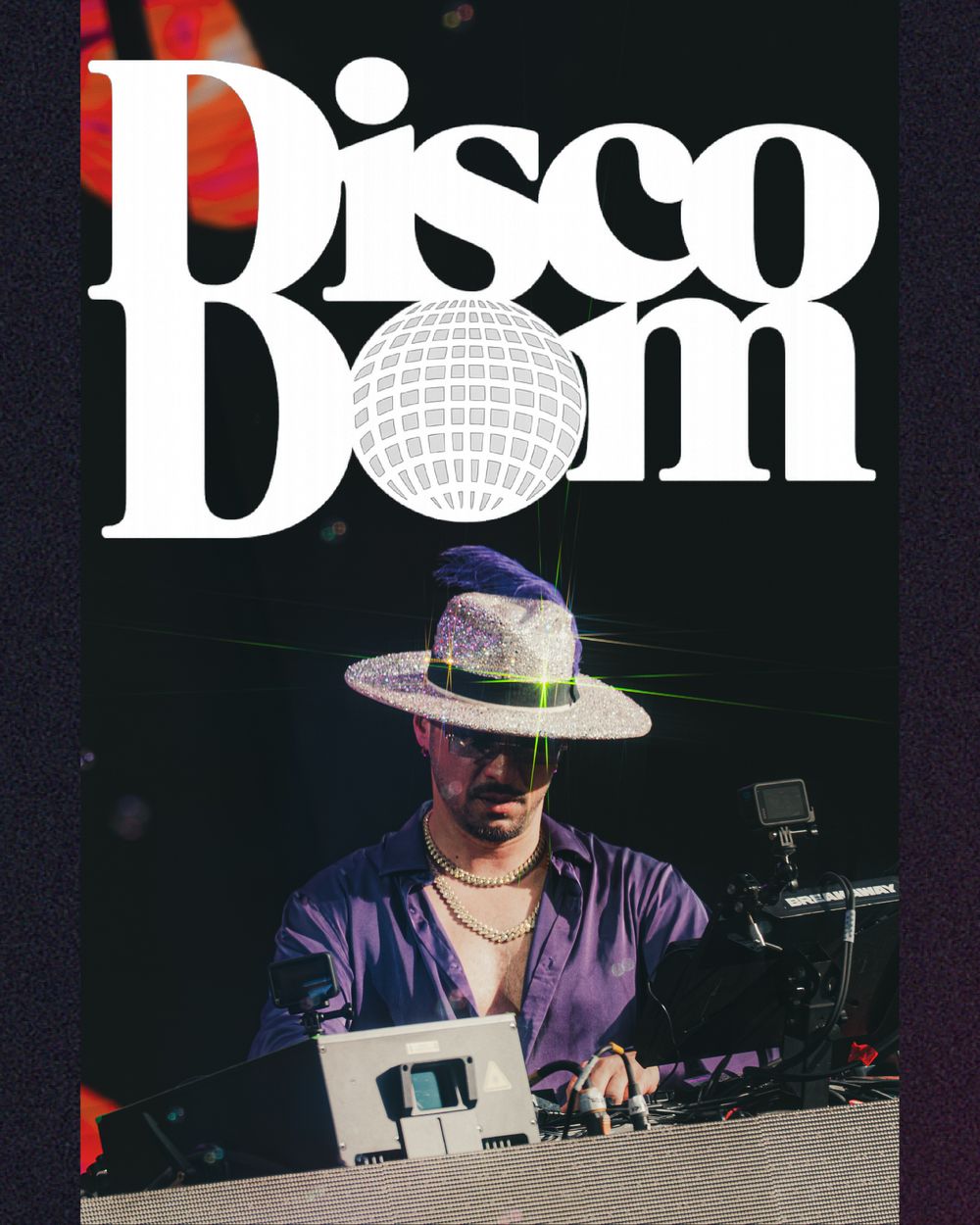 DJ performing at Disco Dom event, wearing a wide-brim hat and purple shirt, mixing at a DJ booth under dramatic stage lighting.