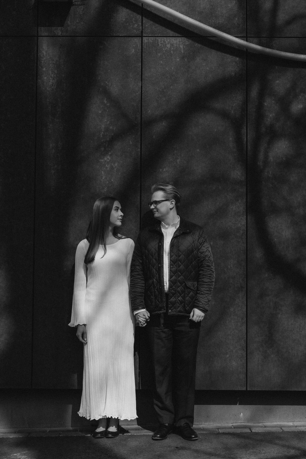A stylish engaged couple standing together by the wall during an editorial engagement photoshoot in Helsinki