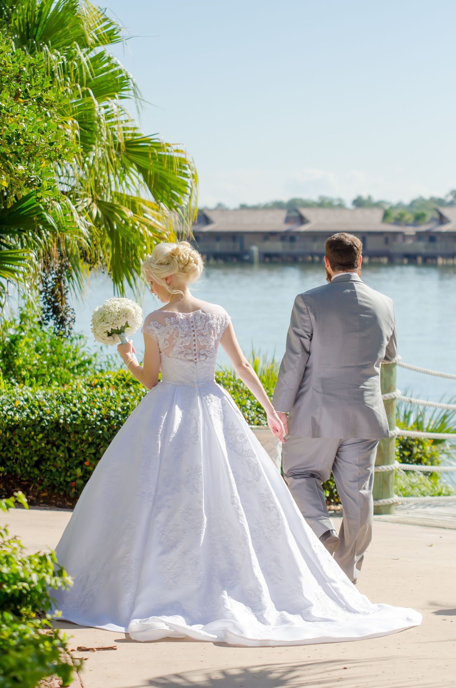 Bride wearing tiara and groom in gray suit share an intimate moment near stained glass windows during wedding ceremony.