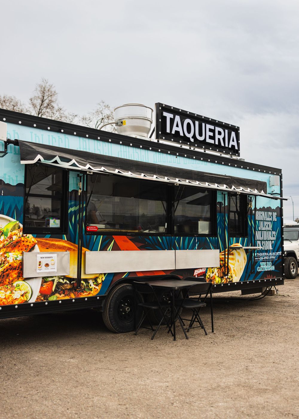 Colorful taqueria food truck with vibrant wrap design and illuminated sign serving authentic Mexican street tacos.