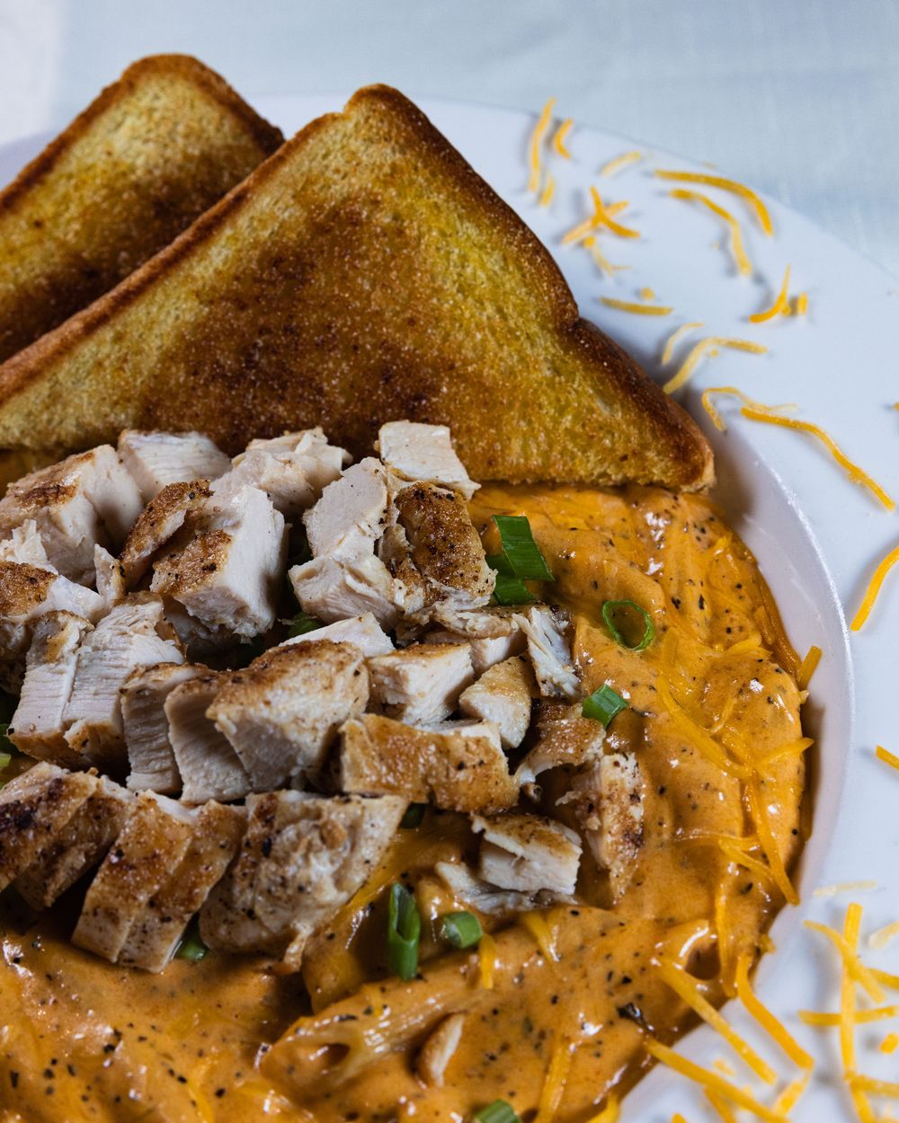 Creamy buffalo chicken bowl topped with diced grilled chicken, green onions, cheddar cheese, and toast.