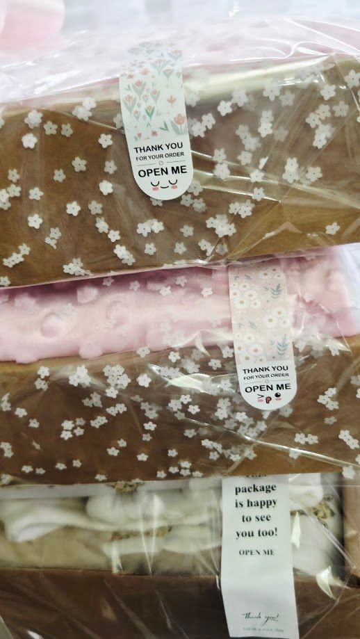Three wrapped gift packages with floral patterns and Thank You Open Me stickers, neatly stacked in clear plastic wrapping.