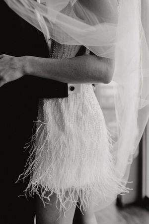 Close up of white feathered wedding dress with delicate tulle veil.
