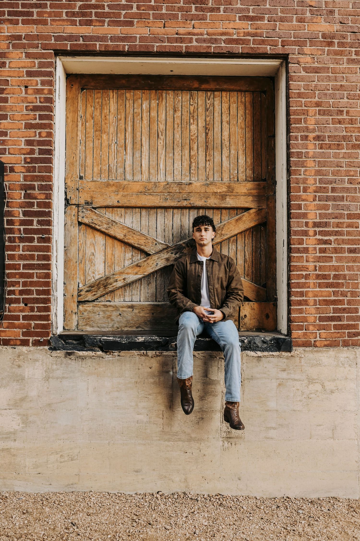 Senior boy portrait at the Flour Mill in McKinney Texas wearing fitted jeans and brown Chelsea boots