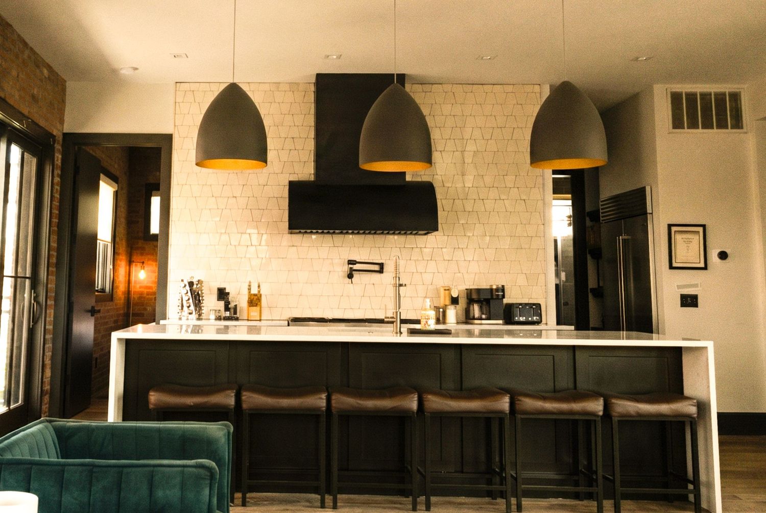 Modern open-concept living room with orange sofa, kitchen bar seating, hardwood floors, and large windows with city views.
