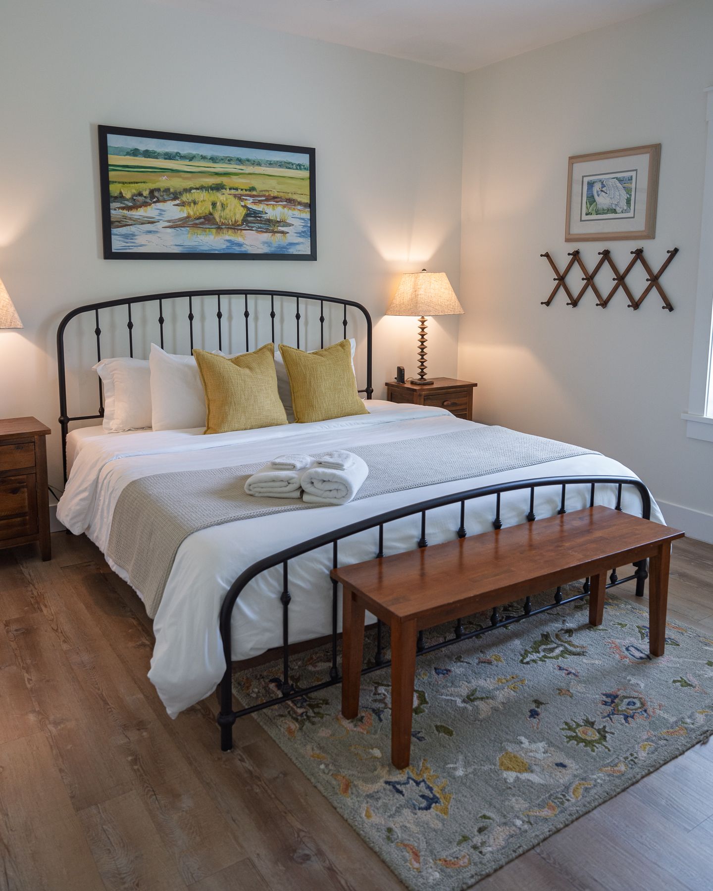Cozy bedroom with black iron bed frame, white bedding, yellow pillows, and warm lighting.