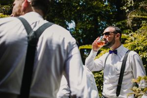 Wedding party members in formal attire gather outdoors on sunny day.