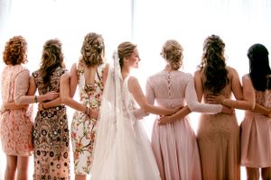 Bridesmaids in blush pink dresses lined up showing backs of their dresses in natural light.