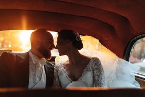Romantic moment captured inside a vintage car at sunset with warm glowing light.