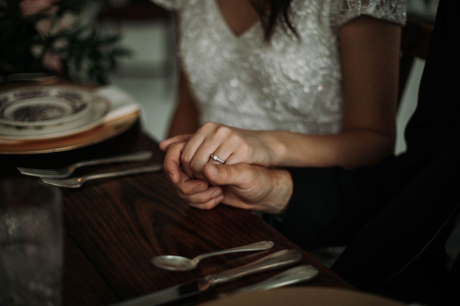 Photo of a bride and groom at the dinner table holding hands