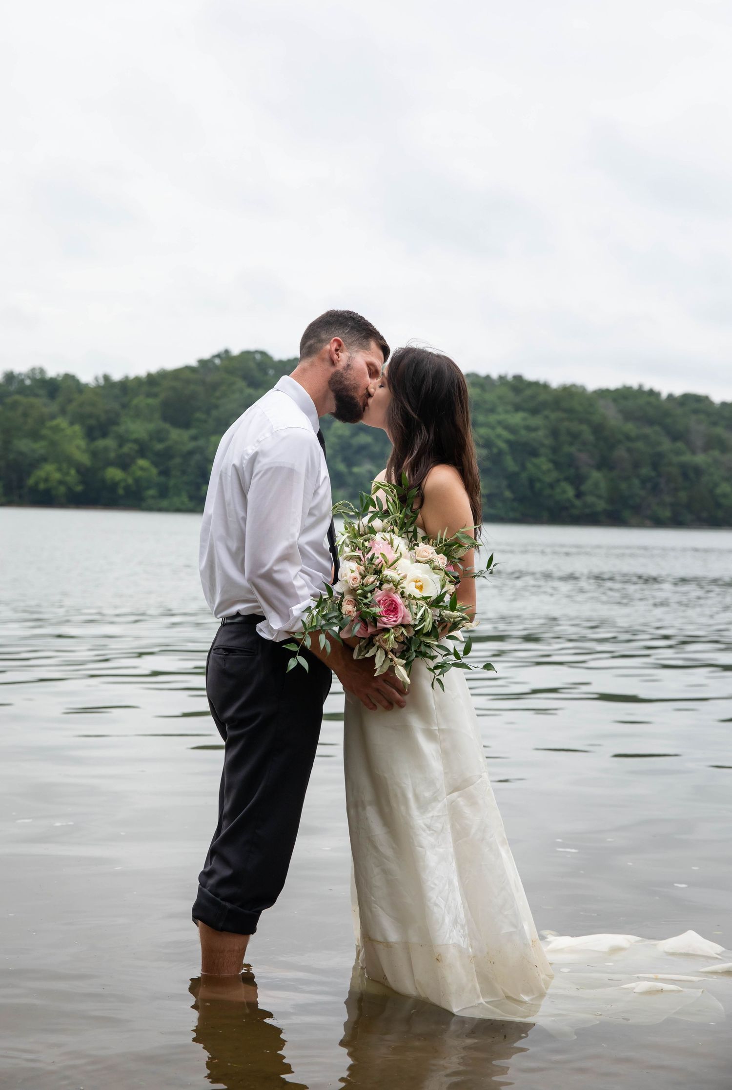 Photo of a bride and groom standing in a lake kissing