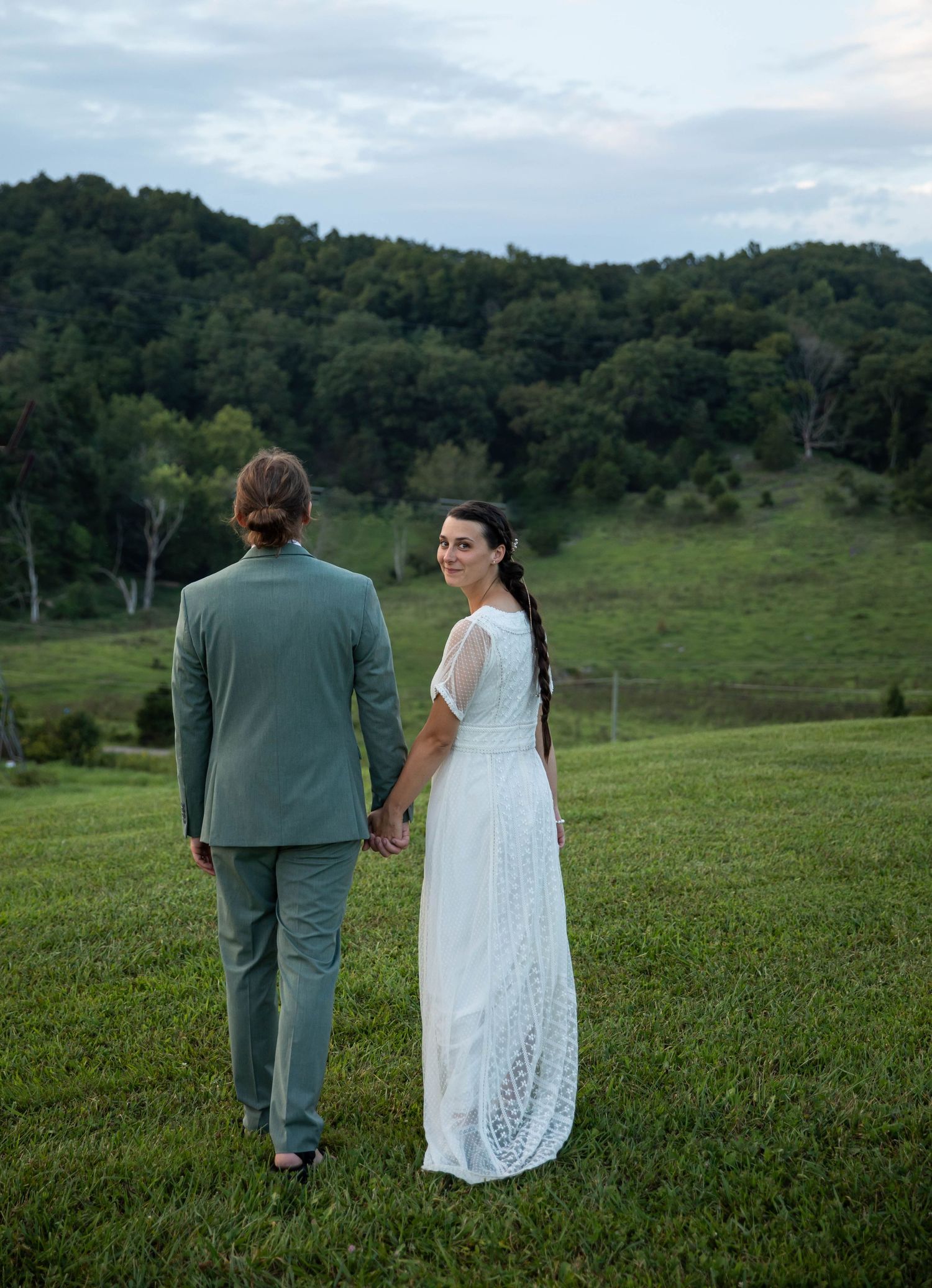 Photo of a bride and groom on a hill, holding hands with the bride looking back at the camera. Abingdon, Virginia wedding photography