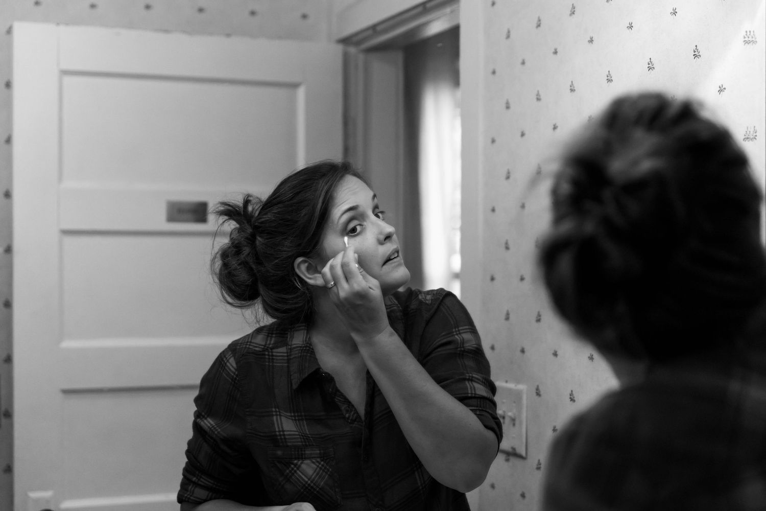 Photo of a bride looking in the mirror, applying her makeup before a mountaintop elopement