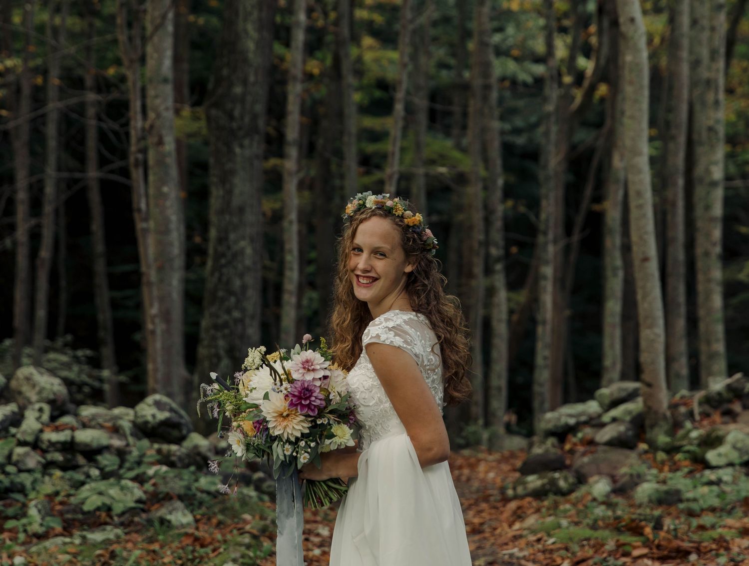 Photo of a bride standing on a trail, holding her wedding bouquet of wildflowers