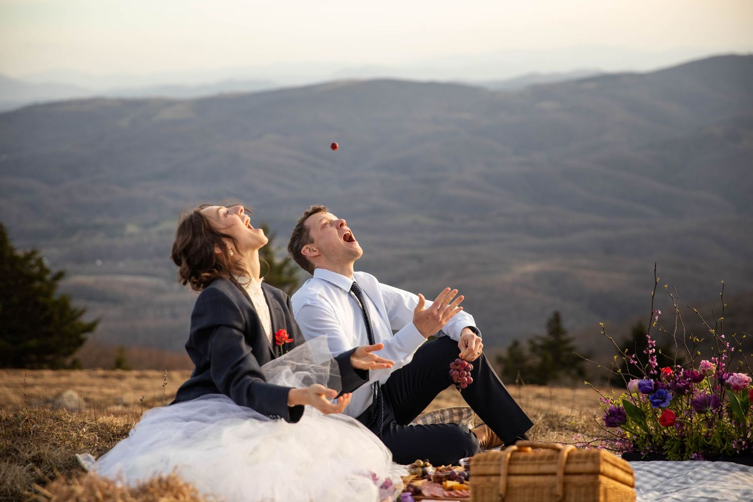 Photo of a bride and groom throwing grapes into the air and catching them in their mouths. Whitetop Mountain elopement