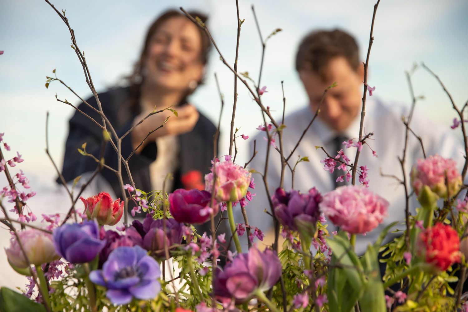 Photo of a bride and groom behind a bouquet of flowers, having a picnic on Whitetop Mountain after bridal portraits