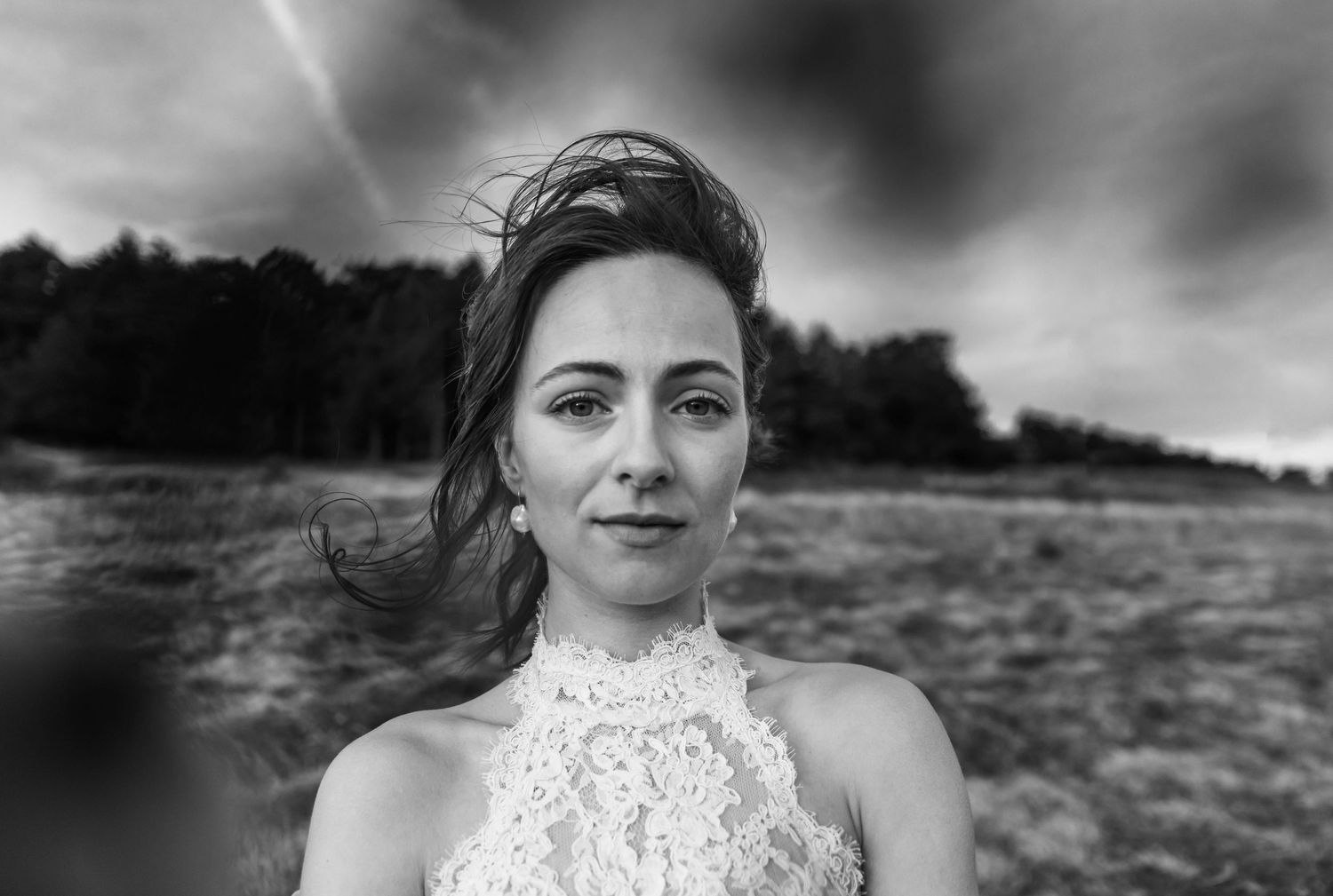 Black and white photo of a bride on a mountaintop with her hair blowing in the wind. Elopement on Whitetop Mountain, southwest Virginia