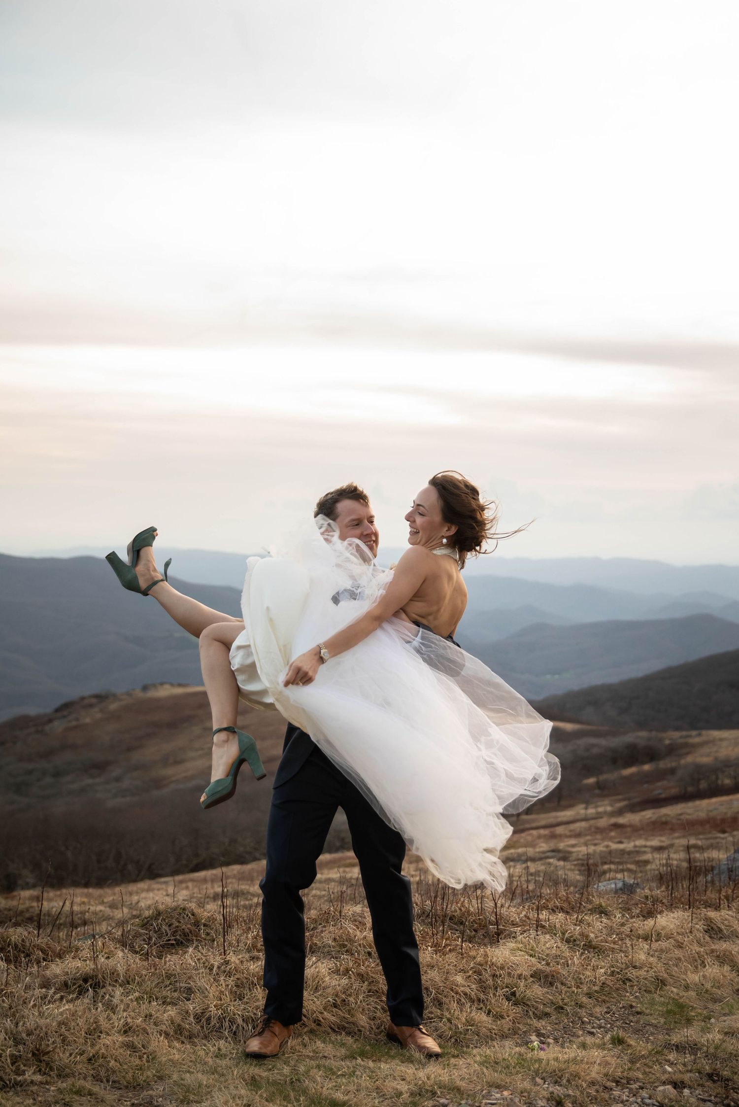 Photo of a groom holding his bride while on top of Whitetop Mountain in Southwest Virginia. Sunset elopement