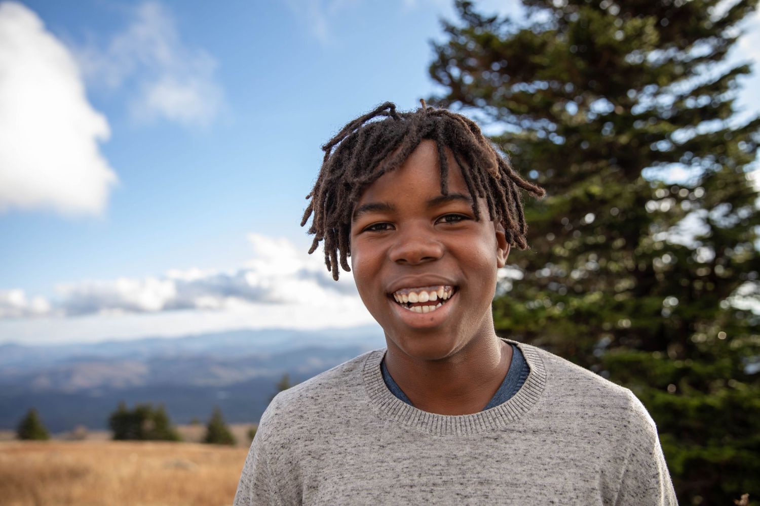 Photo of a boy on a mountain, smiling at the camera during a family photo shoot