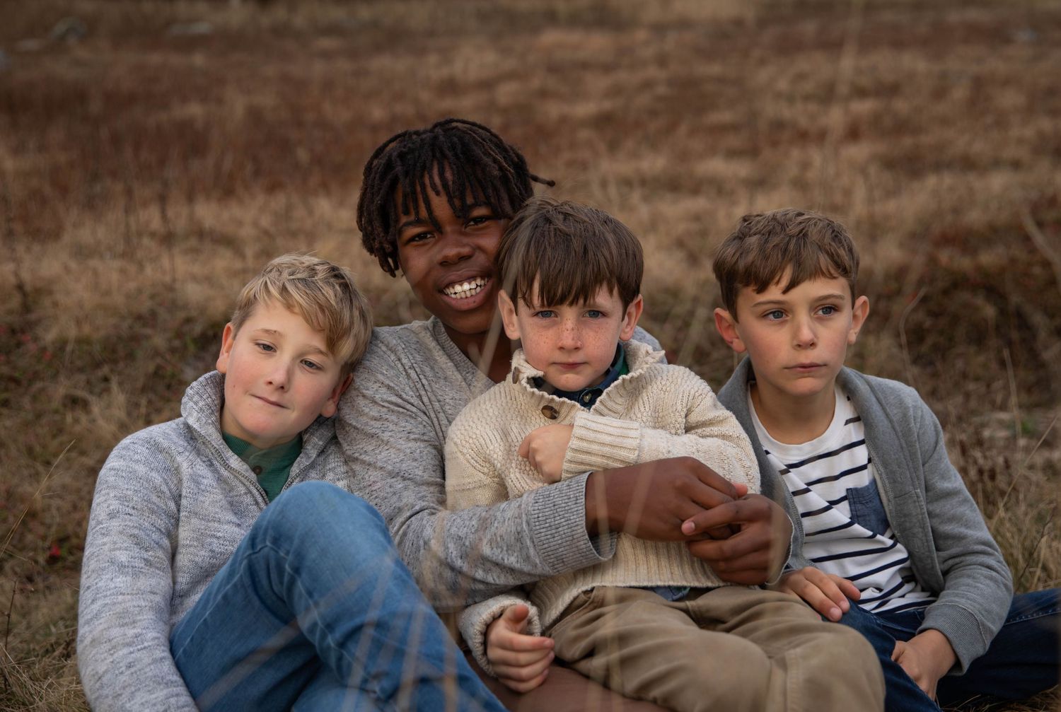Photo of four brothers smiling at the camera during a family photo shoot at sunset on a mountain