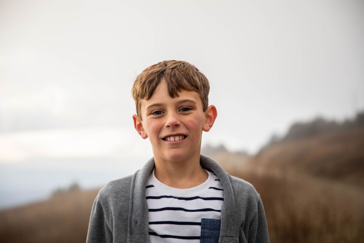 Photo of a boy on a mountain, smiling at the camera during a family photo shoot on Whitetop Mountain, Virginia